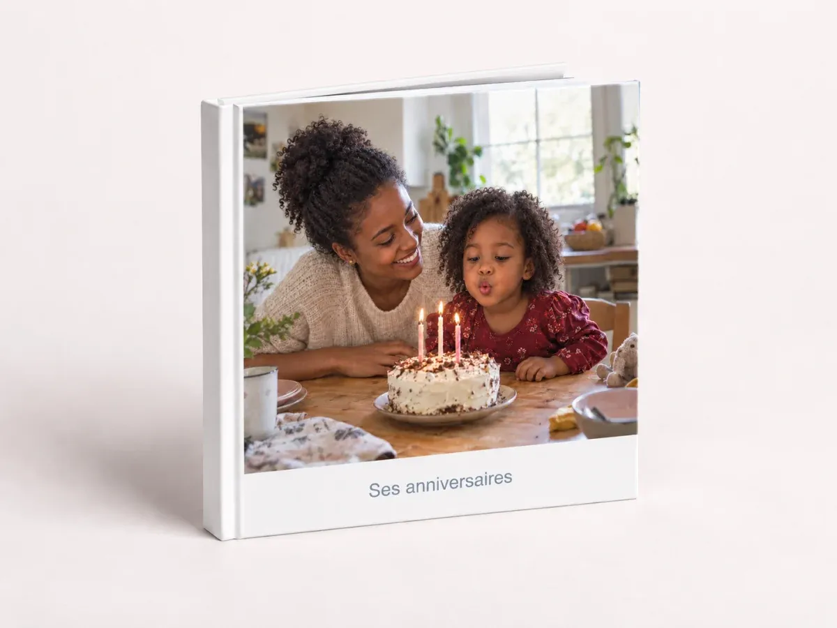 Un livre photo à couverture rigide avec une maman et sa petite fille soufflant les bougies d’un gâteau