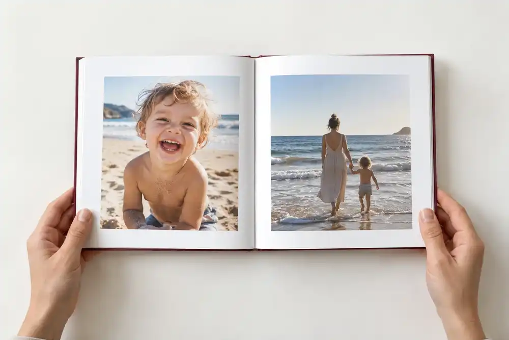 Un livre photo ouvert, simplement tenu entre deux mains sur une table blanche
